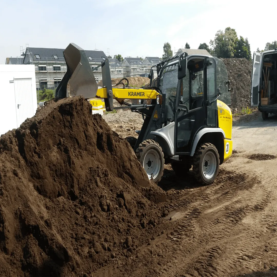 Radlader mit Hubgabel beim Bewegen eines großen Erdhaufens auf einer Baustelle
